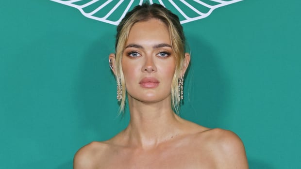Megan Williams poses in front of a teal backdrop in diamond drop earrings and a messy up-do.